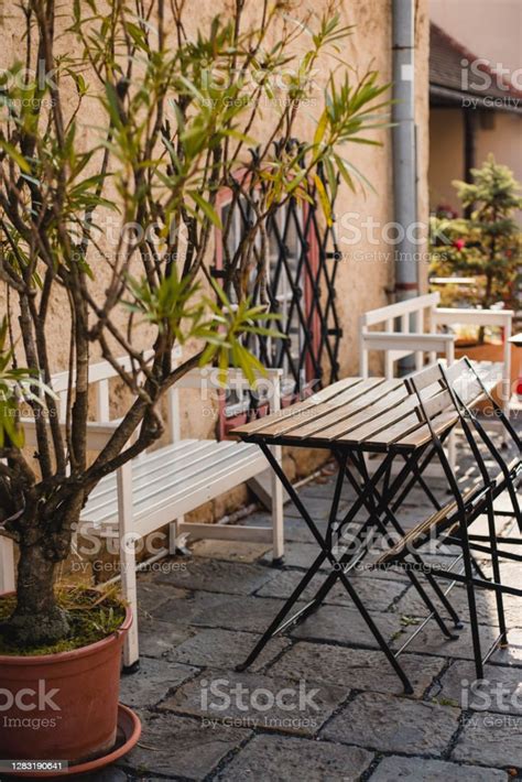 오래된 벽으로 서비스를 위한 야외 거리 카페 테이블 나무 테이블과 의자 아침 시간 빈 카페 테라스 명에 대한 스톡 사진 및