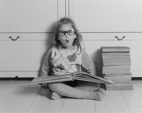 Kid Girl With Glasses And A Stack Of Books Sitting On The Floor Stock