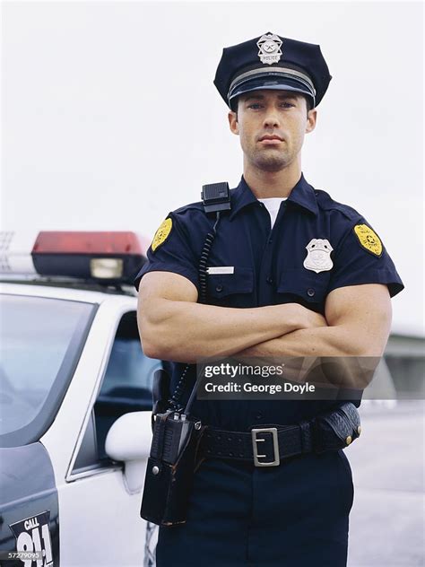 Portrait Of A Policeman Standing With His Arms Folded High Res Stock