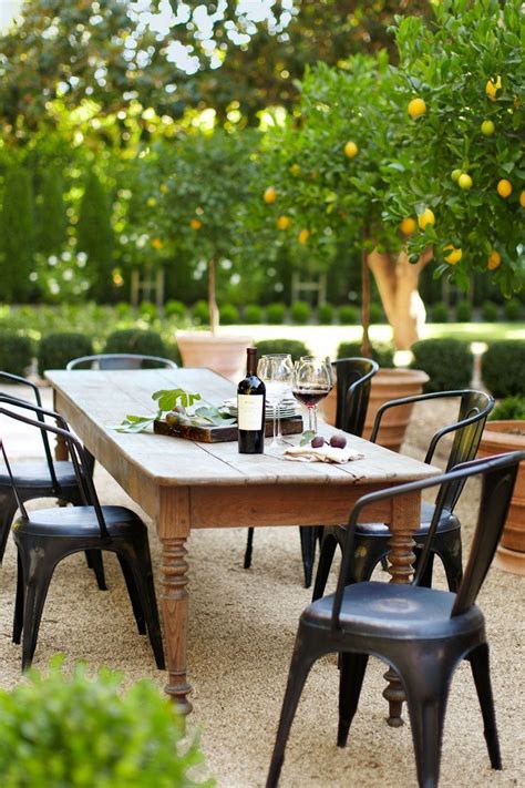 An Outdoor Dining Table With Chairs And Bottles Of Wine On It