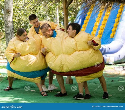 Men And Women In Large Sumo Suits Having Fun In Adventure Park Stock