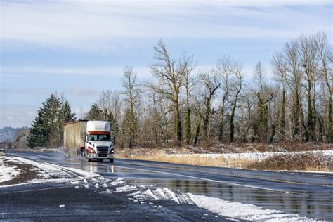 Big Rig Semi Truck With Bulk Semi Trailer Moving On Wet Slippery Winter