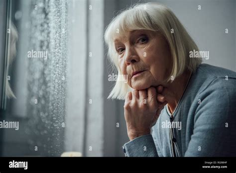 Thoughtful Senior Woman With Grey Hair Propping Chin With Hand And