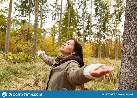 Woman Doing Breathing Exercise In The Forest With Arms Outstretched