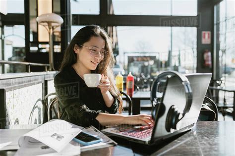 Asian Woman Working While Drinking Coffee In Coffee Shop Stock Photo