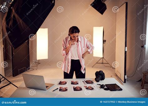 Female Photographer Editing Images From Photo Shoot In Studio Stock