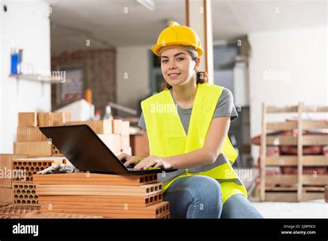 Smiling Female Civil Engineer With Laptop Checking Construction Site
