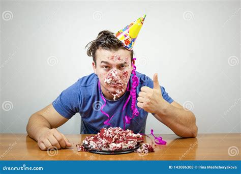 portrait unhappy good looking birthday guy with cake on face showing thumb up unhappy with