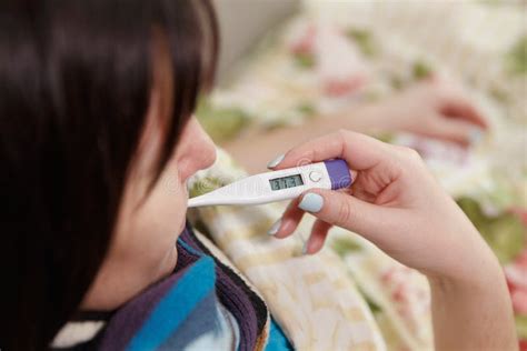 Sick Woman Measures Her Body Temperature With A Thermometer Stock Photo