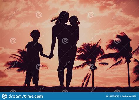 Madre Y Dos Hijos Caminando En La Playa De La Puesta De Sol Imagen De