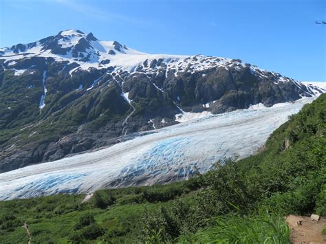 There Is A Large Glacier On The Side Of A Mountain With Blue And White Ice