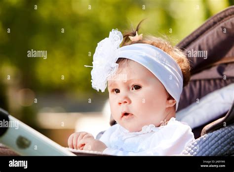 Portrait Of The Little Baby Girl Sitting In A Childrens Carriage In