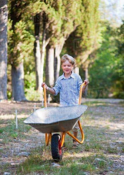 Boy Pushing Wheelbarrow Outdoors Stock Photo Dissolve