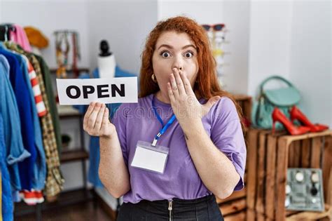 Young Redhead Woman Holding Banner With Open Text At Retail Shop Covering Mouth With Hand