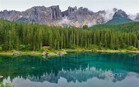 The Mountains Are Reflected In The Clear Blue Water And Green Trees On