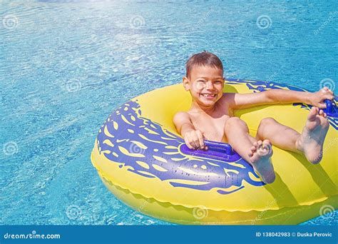 Cheerful Smiling Boy Enjoys Floating On Inflatable Ring In The Swimming