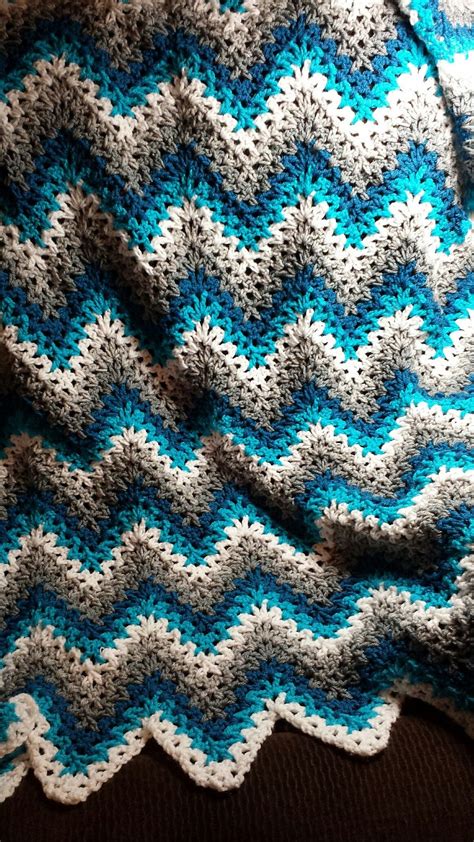 A Blue And White Crocheted Blanket Sitting On Top Of A Couch