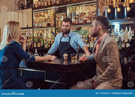 stylish brutal barman serves an attractive couple who spend an evening on a date stock image