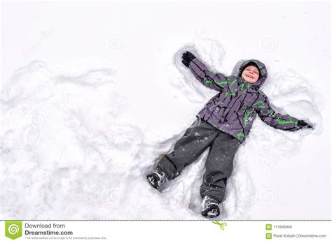 Cute Little Kid Boy In Colorful Winter Clothes Making Snow