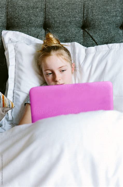 Preteen Girl Streaming A Tv Programme On Her Laptop In Bed By Stocksy Contributor Helen