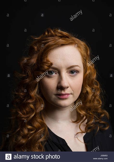 Portrait Serious Woman With Curly Red Hair Against Black Background