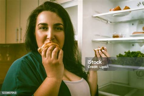 overweight woman eats unhealthy food hungry caucasian woman eats or devours a croissant looking