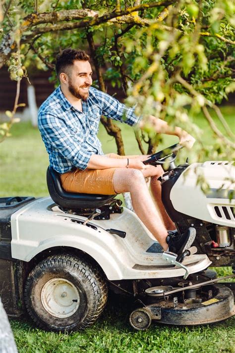Portrait Of Male Worker Using Lawn Tractor For Cutting Grass Stock