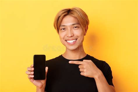 Cheerful Attractive Korean Guy Pointing Finger At Mobile Phone Screen