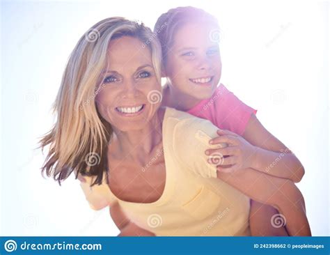 Vacation Fun With Mom A Smiling Mother With Her Daughter On Her Back While Outdoors Stock