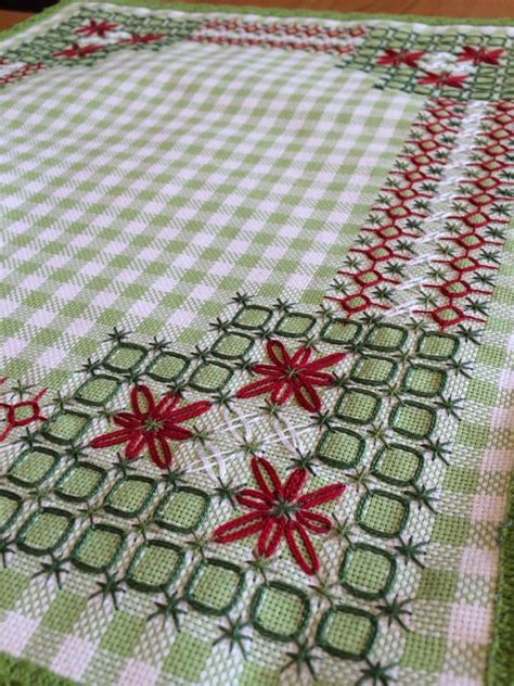 A Green And White Table Cloth With Red Poinsettis On The Border