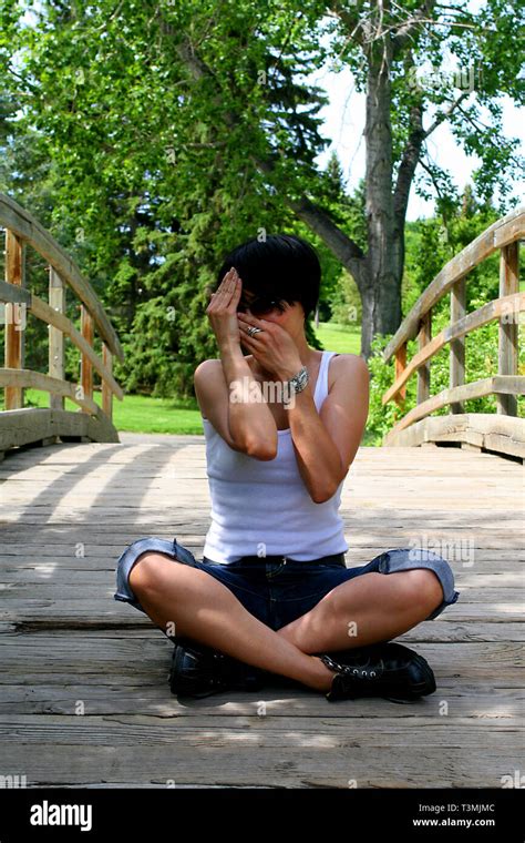 Beautiful Dark Haired Girl Sitting On A Wooden Bridge And Wearing A