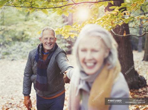 Playful Senior Couple Holding Hands In Autumn Park — Warm Clothing