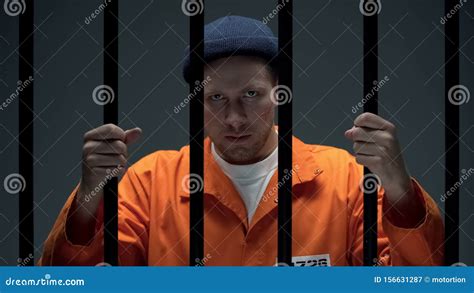 Angry Caucasian Prisoner With Scared Face Looking Through Cell Bars