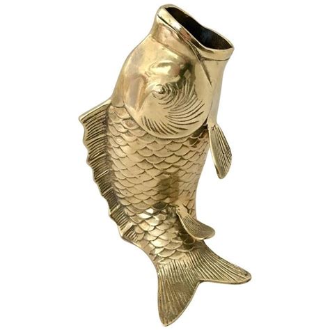 A Gold Fish Shaped Vase Sitting On Top Of A White Surface With Its