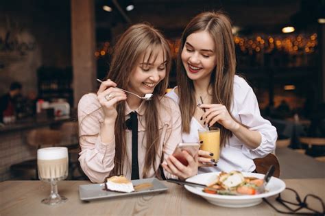 Dos Chicas Almorzando En Una Cafetería Con Teléfono Foto Premium
