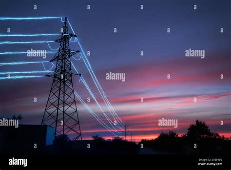 Electric Transmission Towers With Glowing Wires Against The Sunset Sky