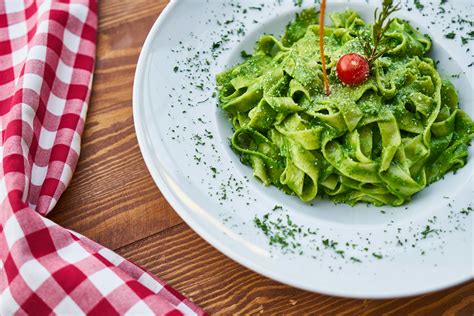 Flat Pasta Noodle With Green Sauce Dish And Cherry Tomato On Top · Free