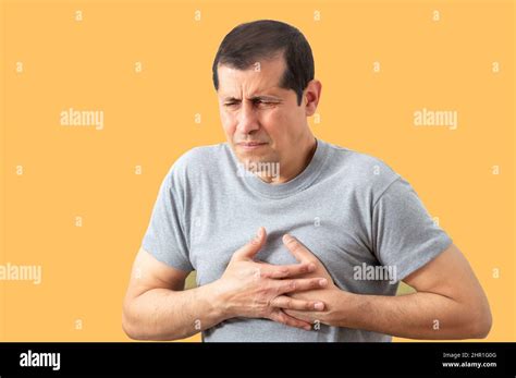 Shot Of A Man Holding His Chest In Discomfort Due To Pain With Yellow Background Heart Attack