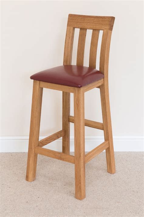 A Wooden Bar Stool With A Red Leather Seat And Backrest In Front Of A