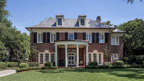 A red brick path lined with a border of yellow day lilies and blue hydrangeas leads up to a beautiful colonial home with portico entry, white siding and sash windows with black shutters below a gray roof. Georgian Style Facade | Red brick house, Colonial house ...