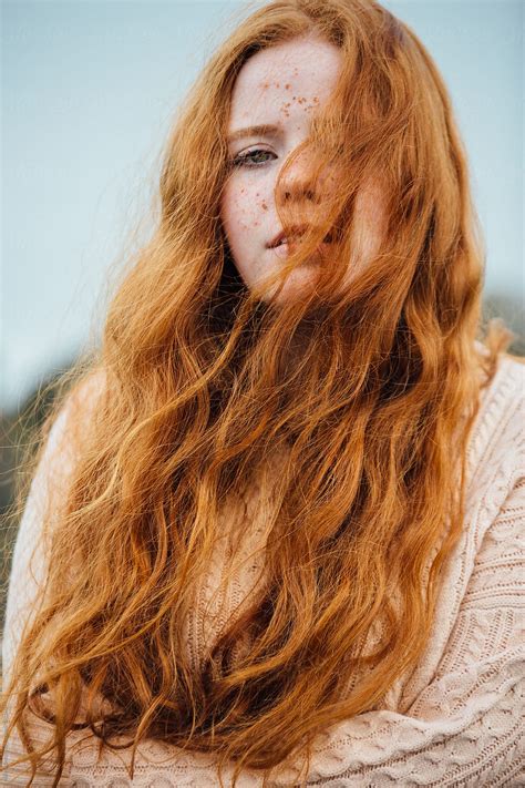 A Babe Woman With Ginger Hair And Freckles With Her Hair Blowing Over Her Face On A Wintery