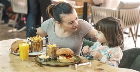 Mamma Med En Gullig Dotter Som äter Snabbmat I Ett Kafé Fotografering för Bildbyråer Bild av