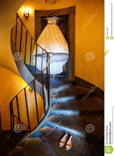 Wedding Dress Hanging On A Spiral Staircase And Wedding Shoes Stock
