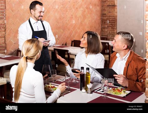 Young Man Waiter Receiving Order From Guests In Country Restaurant