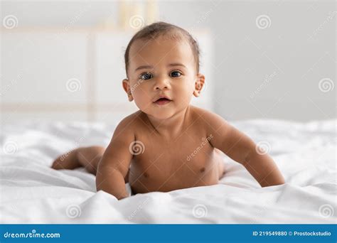 Curious Adorable Little African American Infant Lying Crawling On Bed