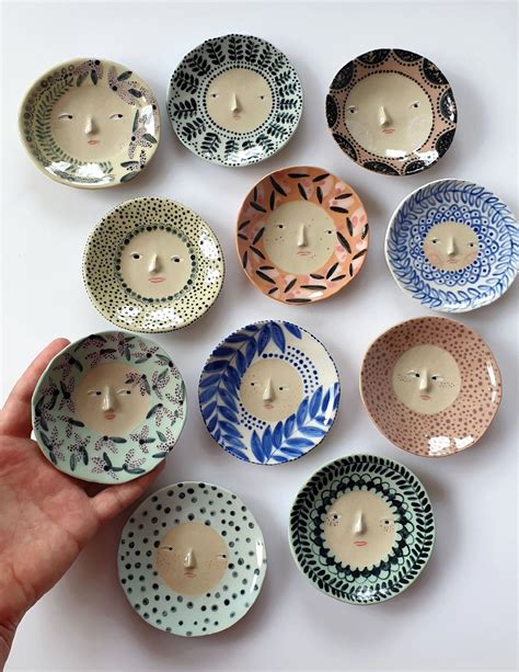 A Hand Is Holding A Small Bowl With Many Designs On It And There Are