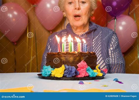 Senior Woman Blowing Out Candles On Cake Stock Photo Image Of Aging