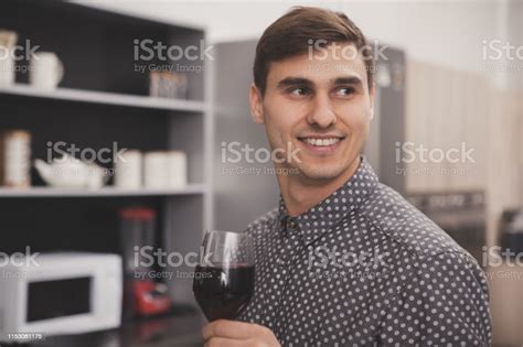 Handsome Man Drinking Wine At Home In The Kitchen Stock Photo
