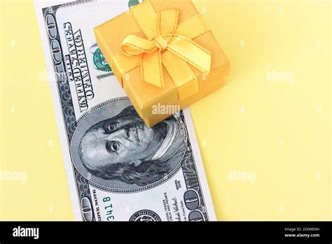 One Hundred Dollar Bill And Yellow Jewelry T Box On Pale Yellow