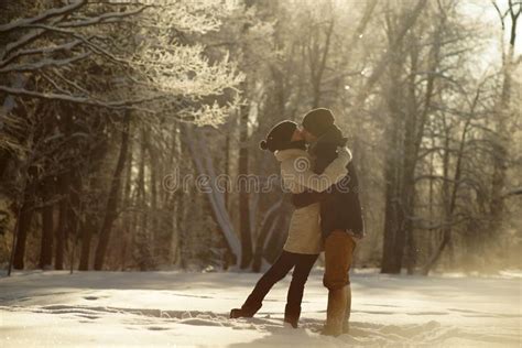 Young Couple Hugging And Kissing In Sunny Snowy Forest Background Of Icy Trees Winter Love